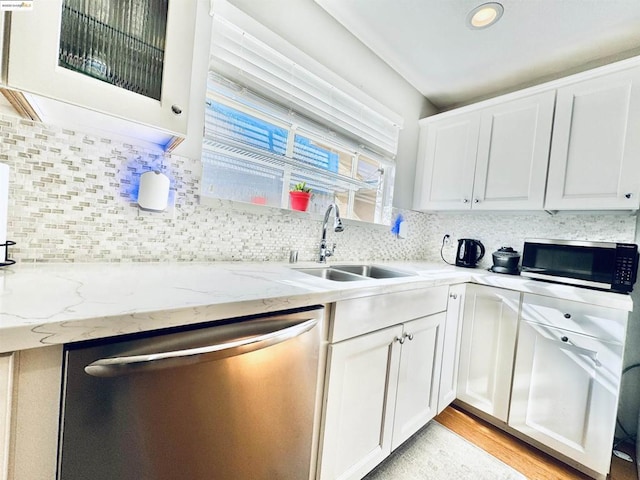 kitchen featuring stainless steel appliances, white cabinetry, light stone countertops, and sink