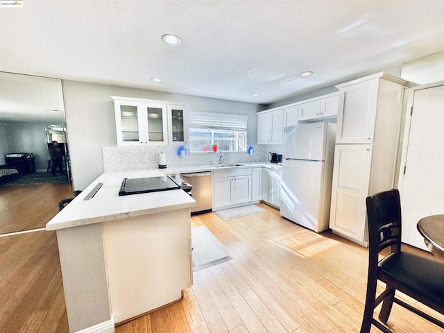 kitchen featuring white cabinetry, dishwasher, white fridge, kitchen peninsula, and light wood-type flooring