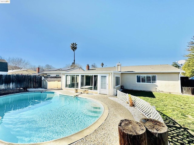 rear view of property featuring a fenced in pool, a yard, and solar panels