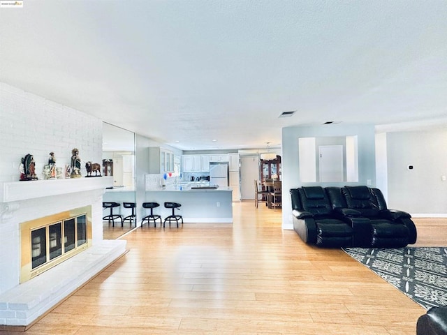 living room with a brick fireplace and light wood-type flooring