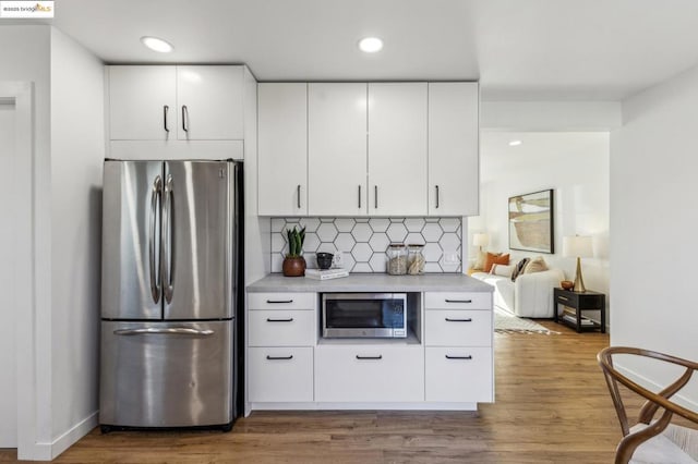 kitchen featuring decorative backsplash, dark wood-type flooring, stainless steel appliances, and white cabinets