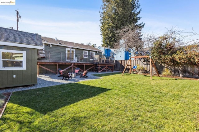 view of yard with a storage shed, a fire pit, a playground, and a wooden deck