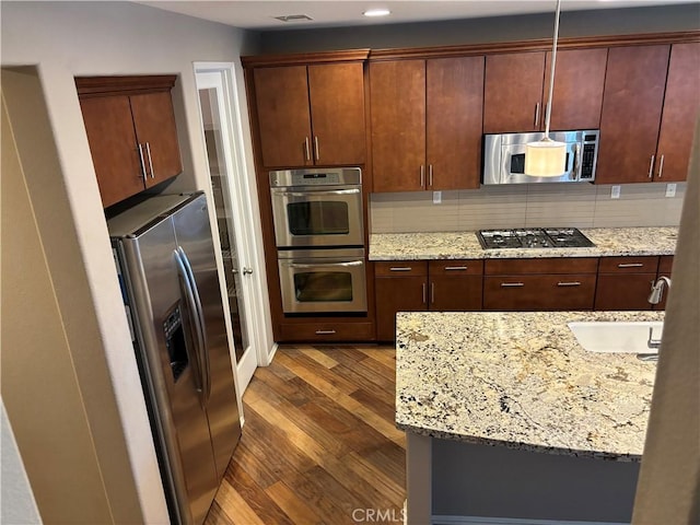 kitchen featuring dark wood-type flooring, sink, appliances with stainless steel finishes, light stone countertops, and backsplash