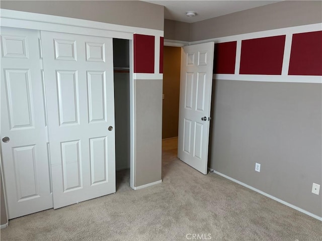 unfurnished bedroom with light colored carpet and a closet