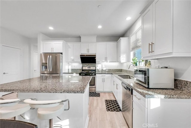 kitchen featuring stone counters, stainless steel appliances, sink, and white cabinets