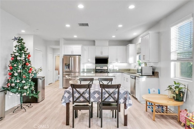 kitchen with white cabinetry, light hardwood / wood-style flooring, stainless steel appliances, and stone countertops