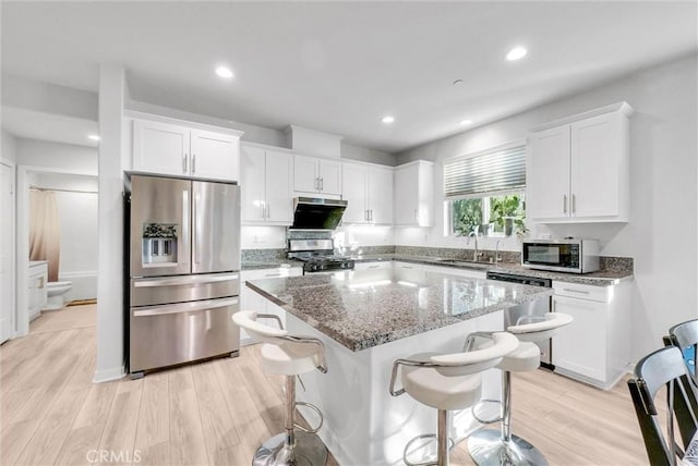 kitchen featuring sink, a breakfast bar area, white cabinetry, appliances with stainless steel finishes, and a kitchen island