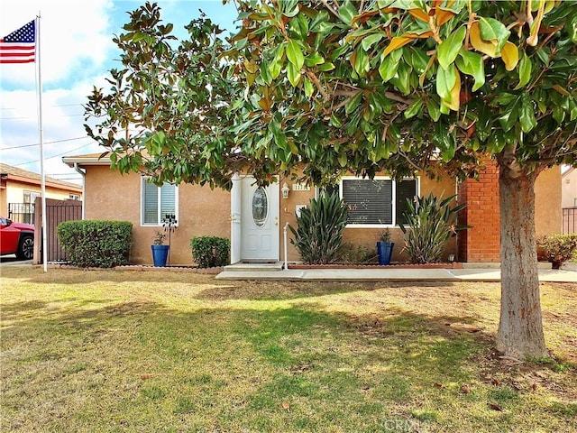 obstructed view of property featuring a front yard, fence, and stucco siding