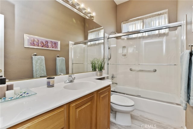 full bathroom with enclosed tub / shower combo, vanity, and toilet