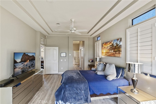 bedroom featuring light hardwood / wood-style floors, a raised ceiling, and ceiling fan