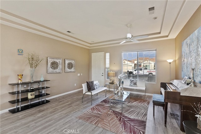 living room featuring a tray ceiling, wood-type flooring, and ceiling fan