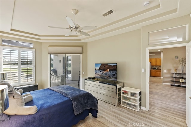 bedroom with light hardwood / wood-style flooring and a raised ceiling