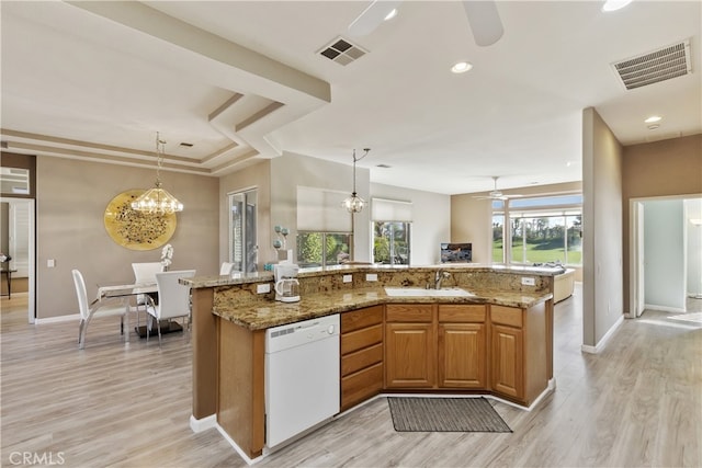 kitchen featuring sink, light stone counters, hanging light fixtures, dishwasher, and light hardwood / wood-style floors