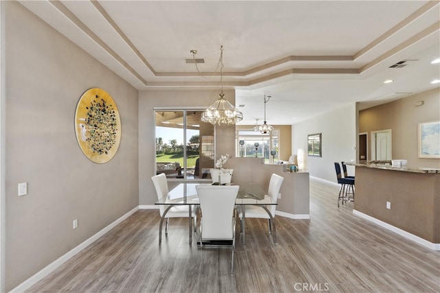 dining space featuring a chandelier, a raised ceiling, and hardwood / wood-style floors