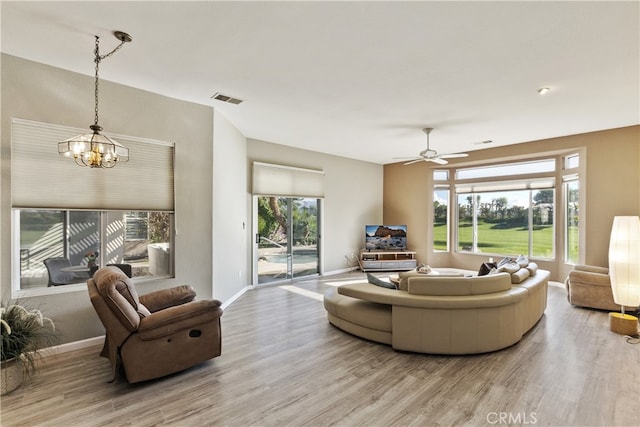 living room with ceiling fan with notable chandelier and light wood-type flooring