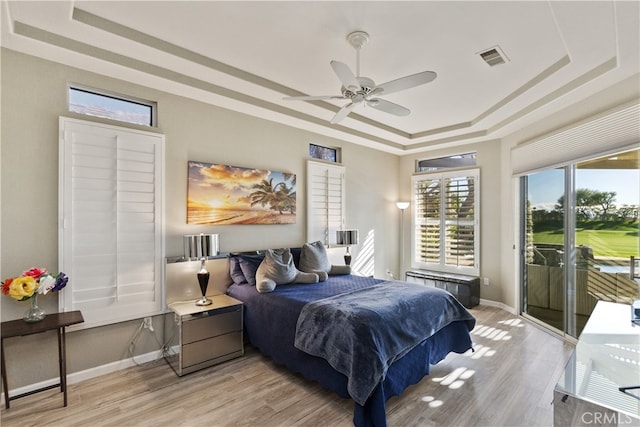 bedroom with radiator, access to outside, ceiling fan, a raised ceiling, and light wood-type flooring