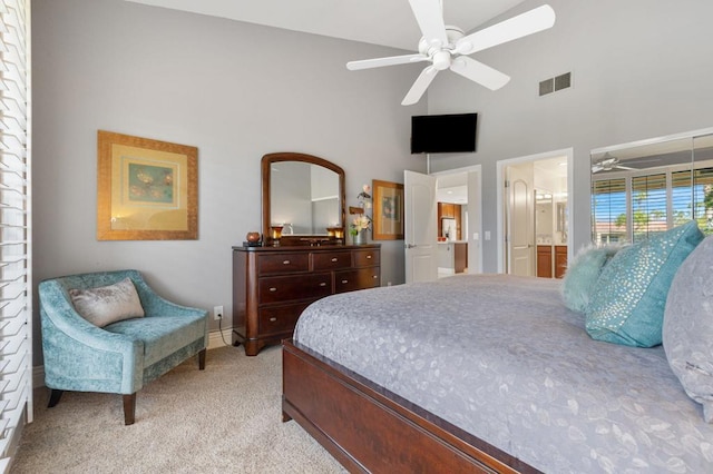 bedroom featuring ceiling fan, a towering ceiling, connected bathroom, and light carpet