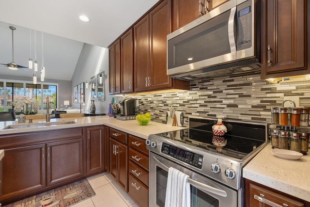 kitchen featuring vaulted ceiling, pendant lighting, tasteful backsplash, light tile patterned floors, and stainless steel appliances