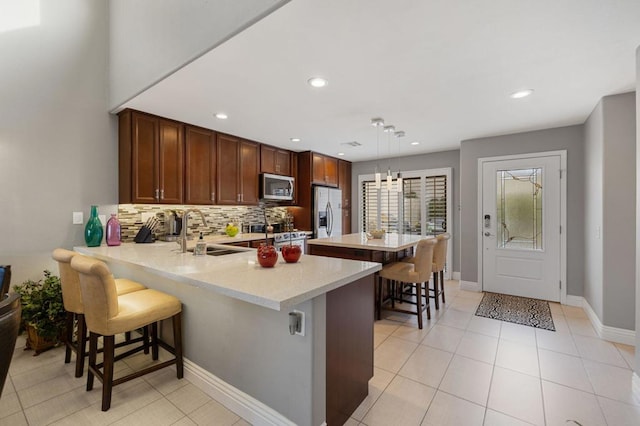 kitchen featuring sink, appliances with stainless steel finishes, hanging light fixtures, a kitchen breakfast bar, and kitchen peninsula