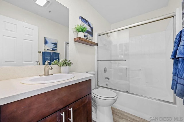 full bathroom with enclosed tub / shower combo, wood-type flooring, vanity, and toilet