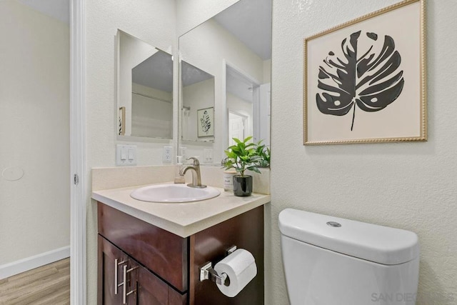 bathroom featuring vanity, hardwood / wood-style floors, and toilet