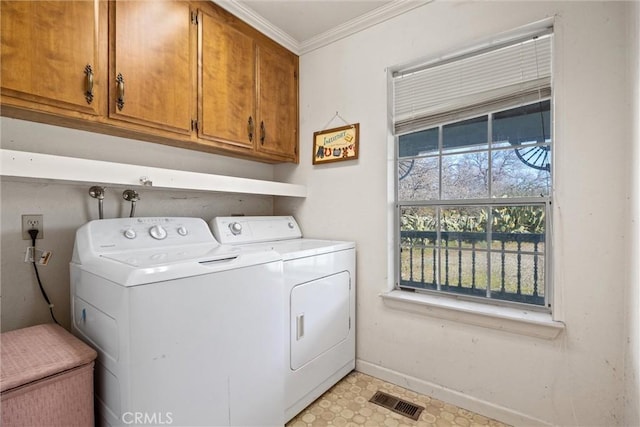 clothes washing area with crown molding, cabinets, and washer and dryer