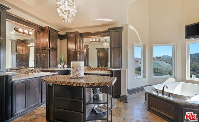 bathroom with vanity, a bath, and a chandelier