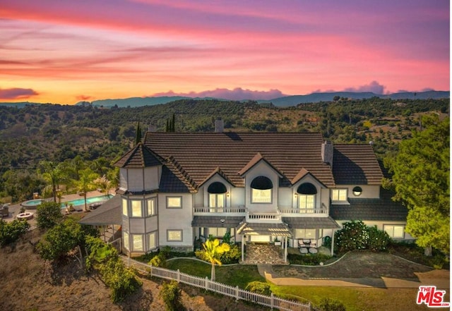 back house at dusk featuring a balcony and a mountain view