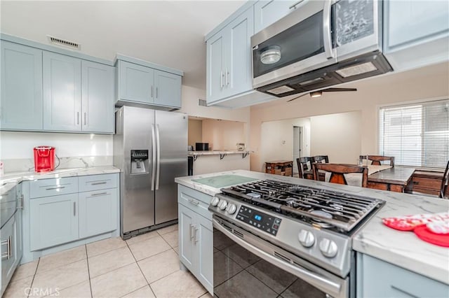 kitchen featuring light tile patterned flooring, appliances with stainless steel finishes, and light stone counters