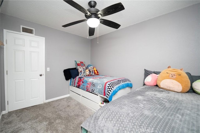 carpeted bedroom featuring ceiling fan and a textured ceiling