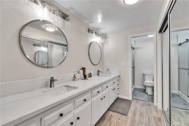 bathroom with a shower with door, vanity, hardwood / wood-style floors, and toilet