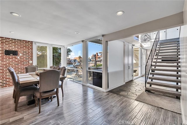 dining room with a wall of windows, brick wall, and hardwood / wood-style floors