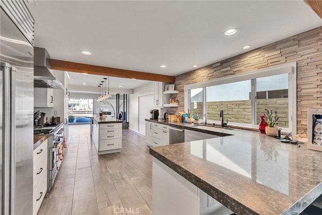 kitchen with sink, hanging light fixtures, a large island with sink, high quality appliances, and white cabinets