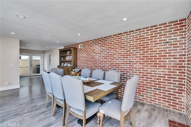 dining area featuring brick wall and hardwood / wood-style floors