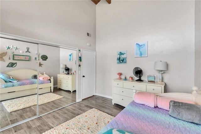 bedroom with a towering ceiling, dark wood-type flooring, and a closet