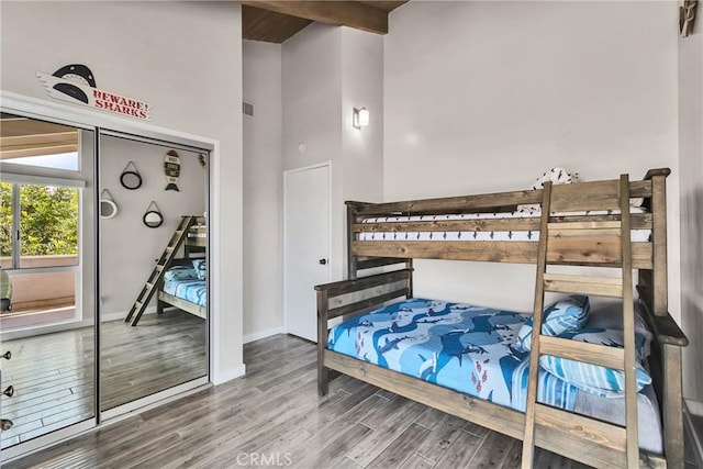 bedroom featuring hardwood / wood-style flooring, a high ceiling, and beamed ceiling