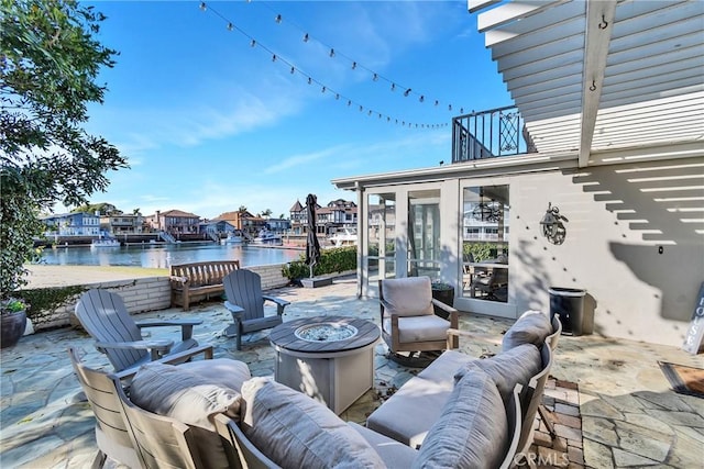 view of patio featuring an outdoor living space with a fire pit, a sunroom, and a water view