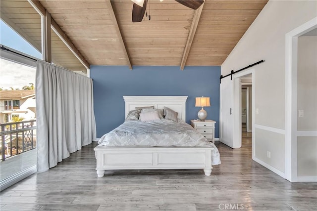 unfurnished bedroom with vaulted ceiling with beams, wood-type flooring, wooden ceiling, access to outside, and a barn door