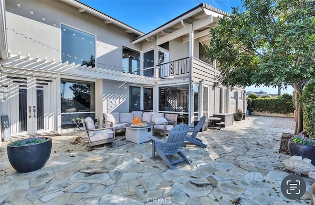 rear view of house featuring a patio, an outdoor living space with a fire pit, and french doors