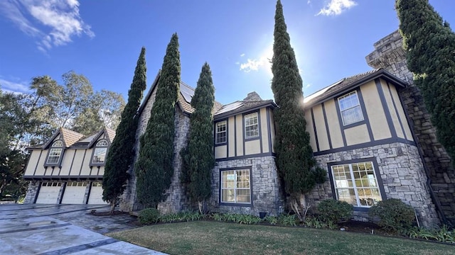 tudor home featuring a garage and a front yard