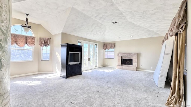 unfurnished living room with vaulted ceiling, light carpet, a textured ceiling, and a fireplace