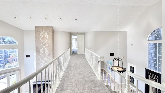 hall with light carpet, a towering ceiling, and plenty of natural light