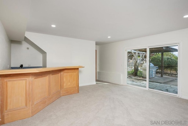 bar featuring light colored carpet and light brown cabinetry