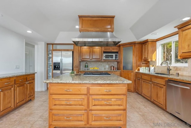 kitchen with stainless steel appliances, light stone countertops, sink, and a kitchen island