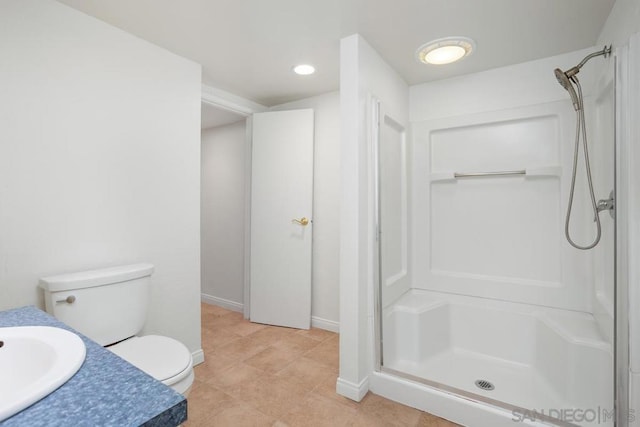 bathroom with a shower, vanity, tile patterned floors, and toilet