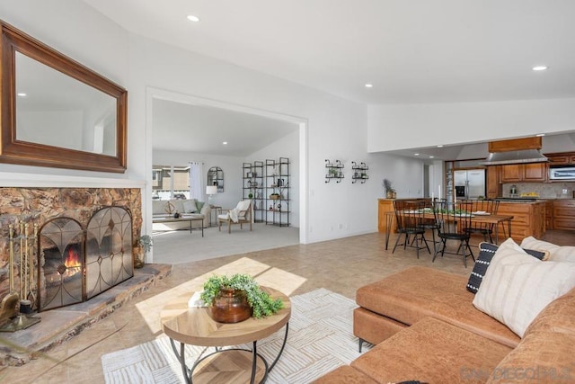 living room with lofted ceiling and a stone fireplace