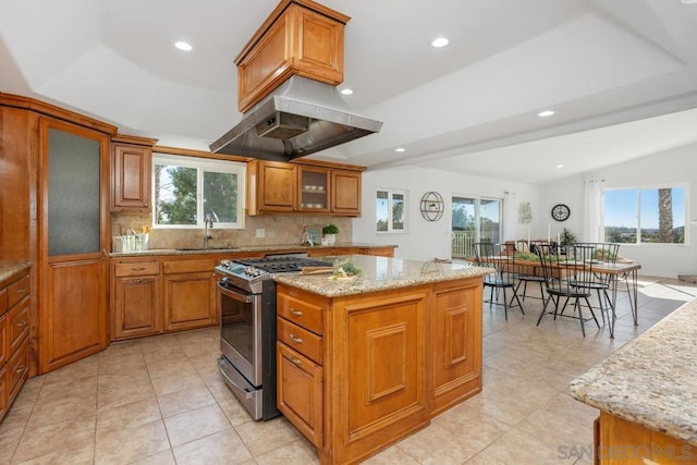 kitchen with a wealth of natural light, stainless steel gas stove, sink, a center island, and light stone countertops