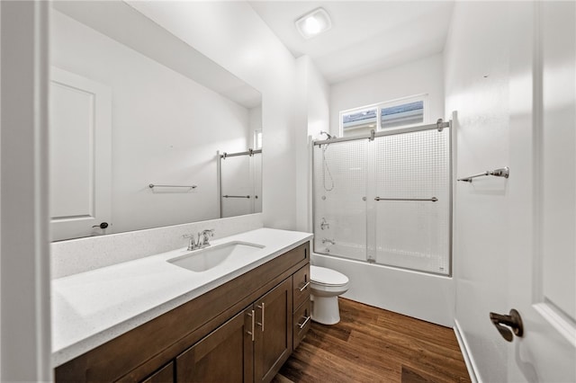 full bathroom with bath / shower combo with glass door, wood-type flooring, toilet, and vanity