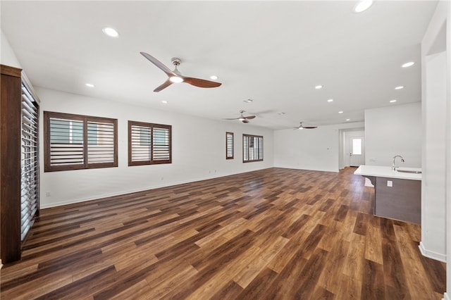 unfurnished living room featuring sink, dark hardwood / wood-style floors, and ceiling fan