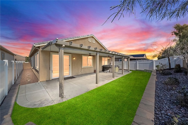 back house at dusk featuring a yard and a patio area